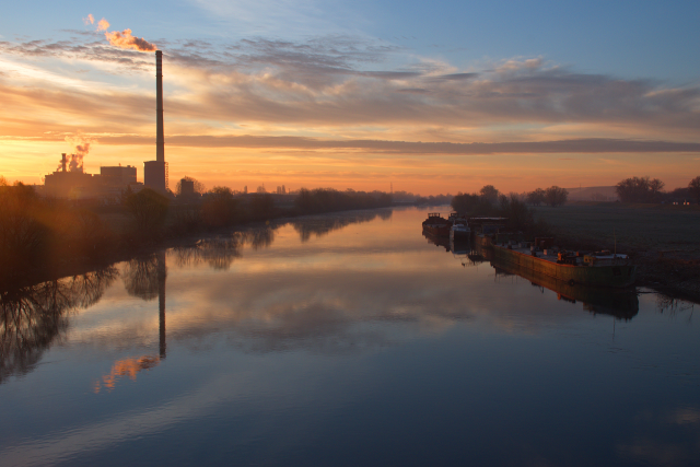 Sunrise on river with chimney reflecting in water